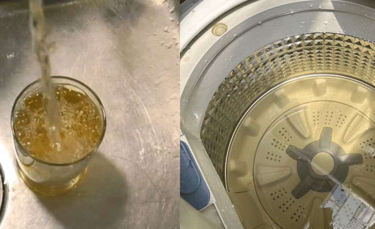 Agua amarilla saliendo de un grifo doméstico en un vaso de vidrio transparente